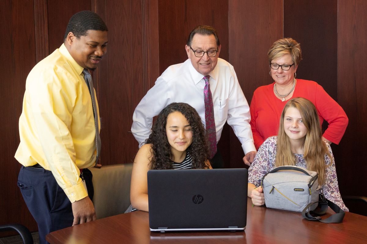 Mayor Perrin looks at students computer as they show him project idea.