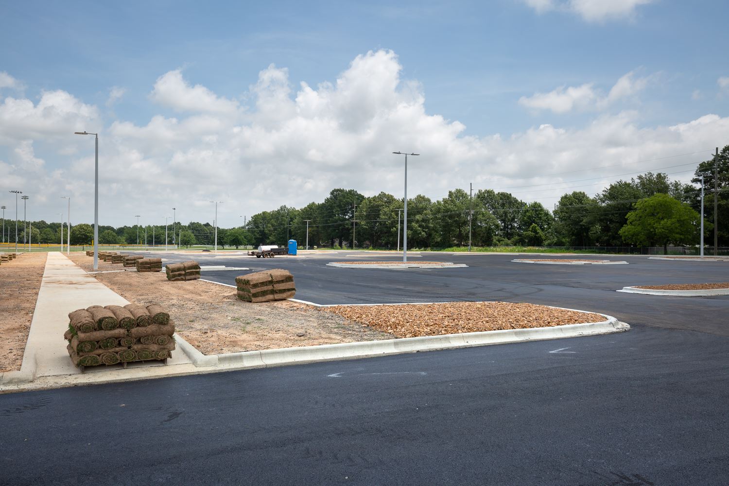 Southside Softball Complex parking lot paved with asphalt and rolls of sod being ready to install.