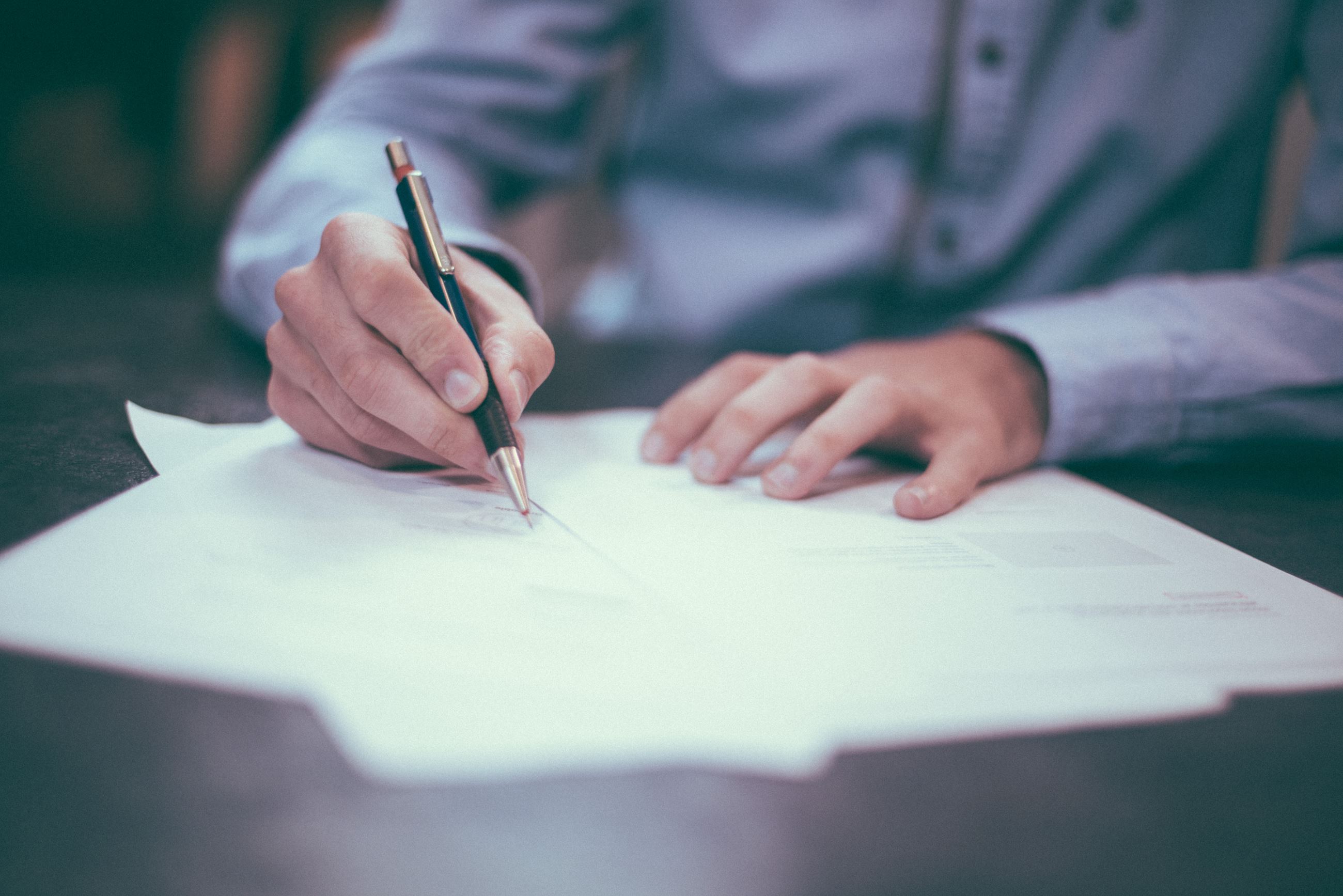 Man writing on papers at desk.