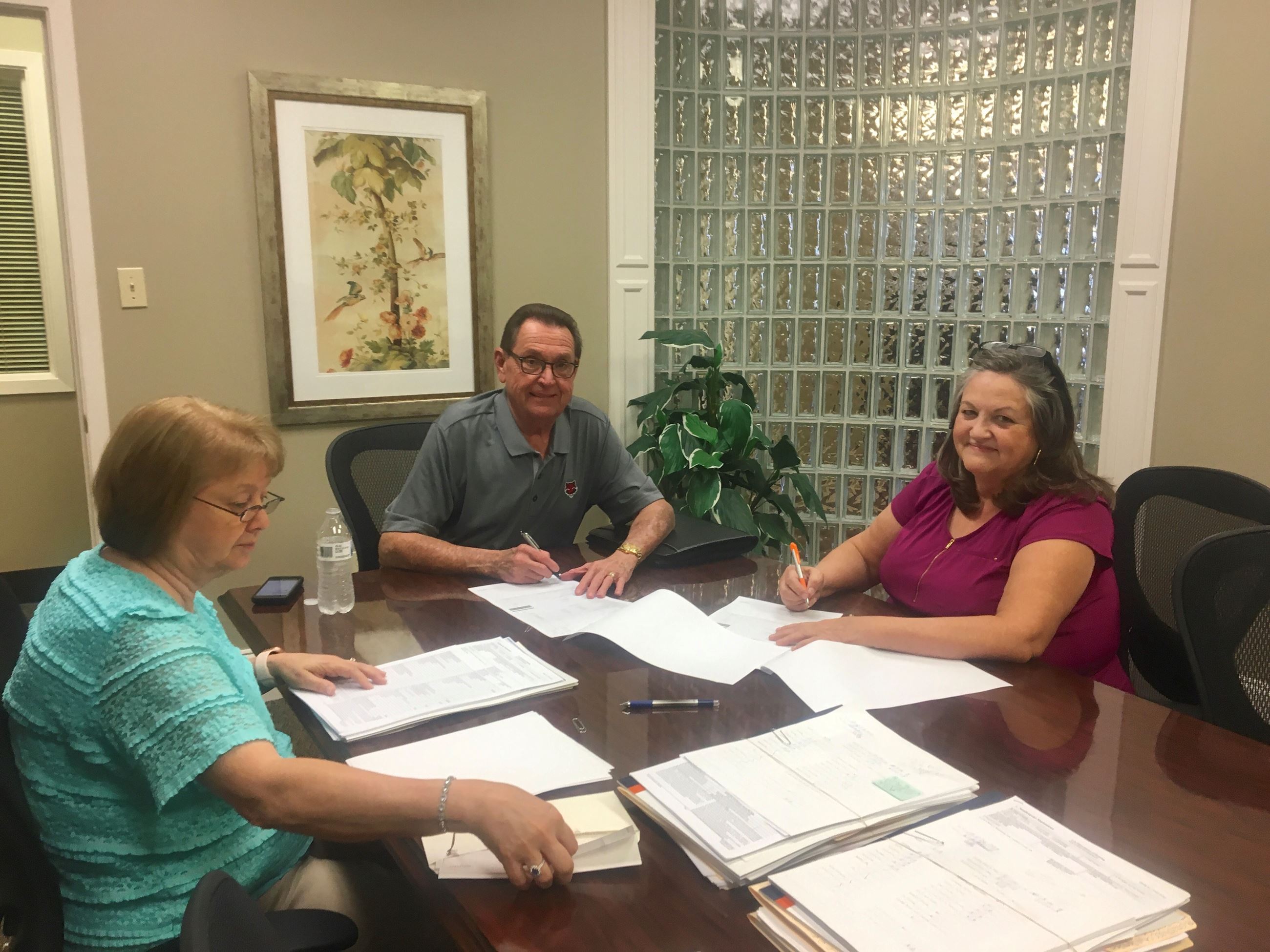 Mayor Perrin and City Clerk Donna Jackson sitting at table as Mayor Perrin signs property deed on Ve