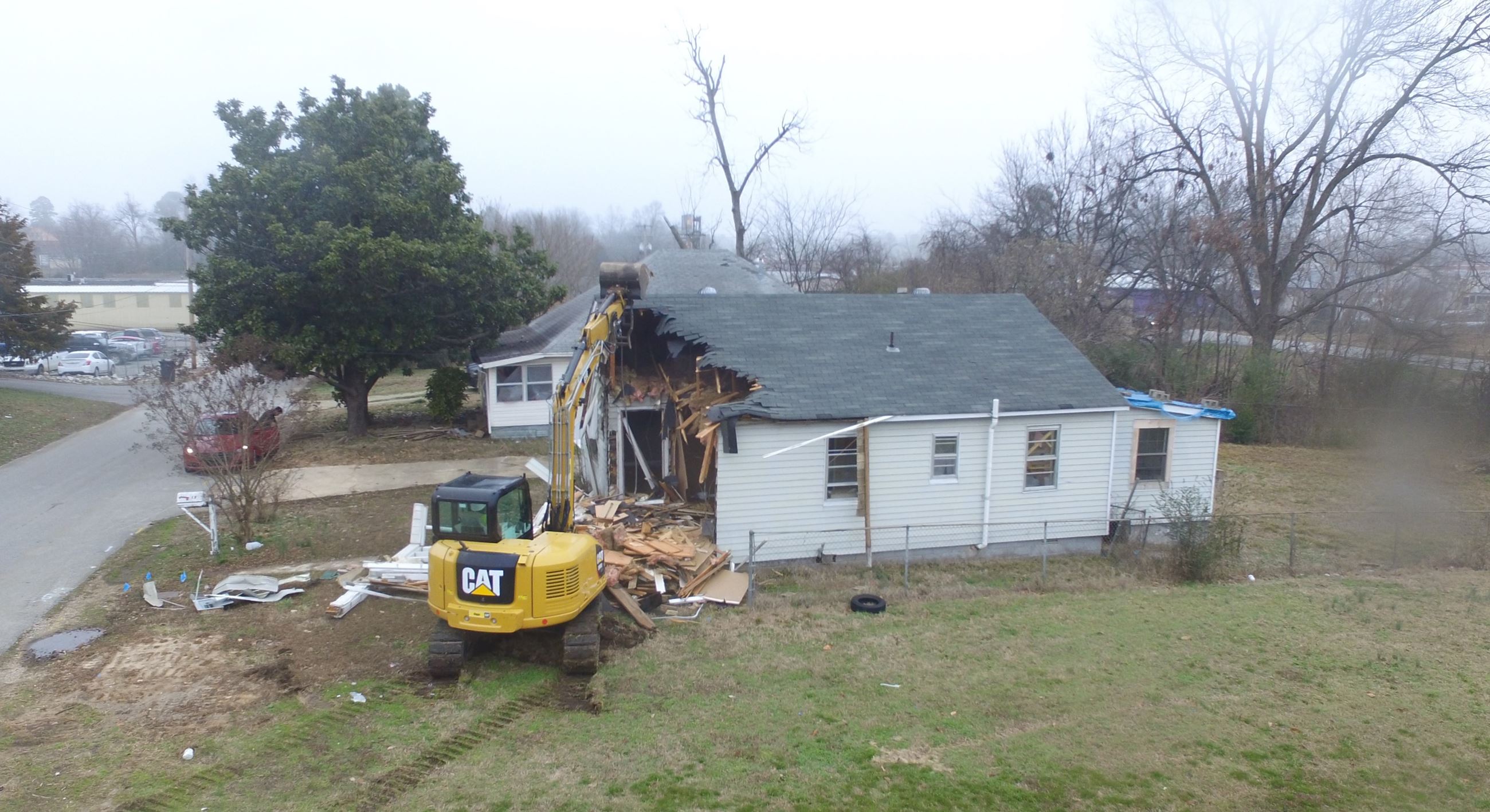 Excavator tearing down house at site of future Veterans' Village