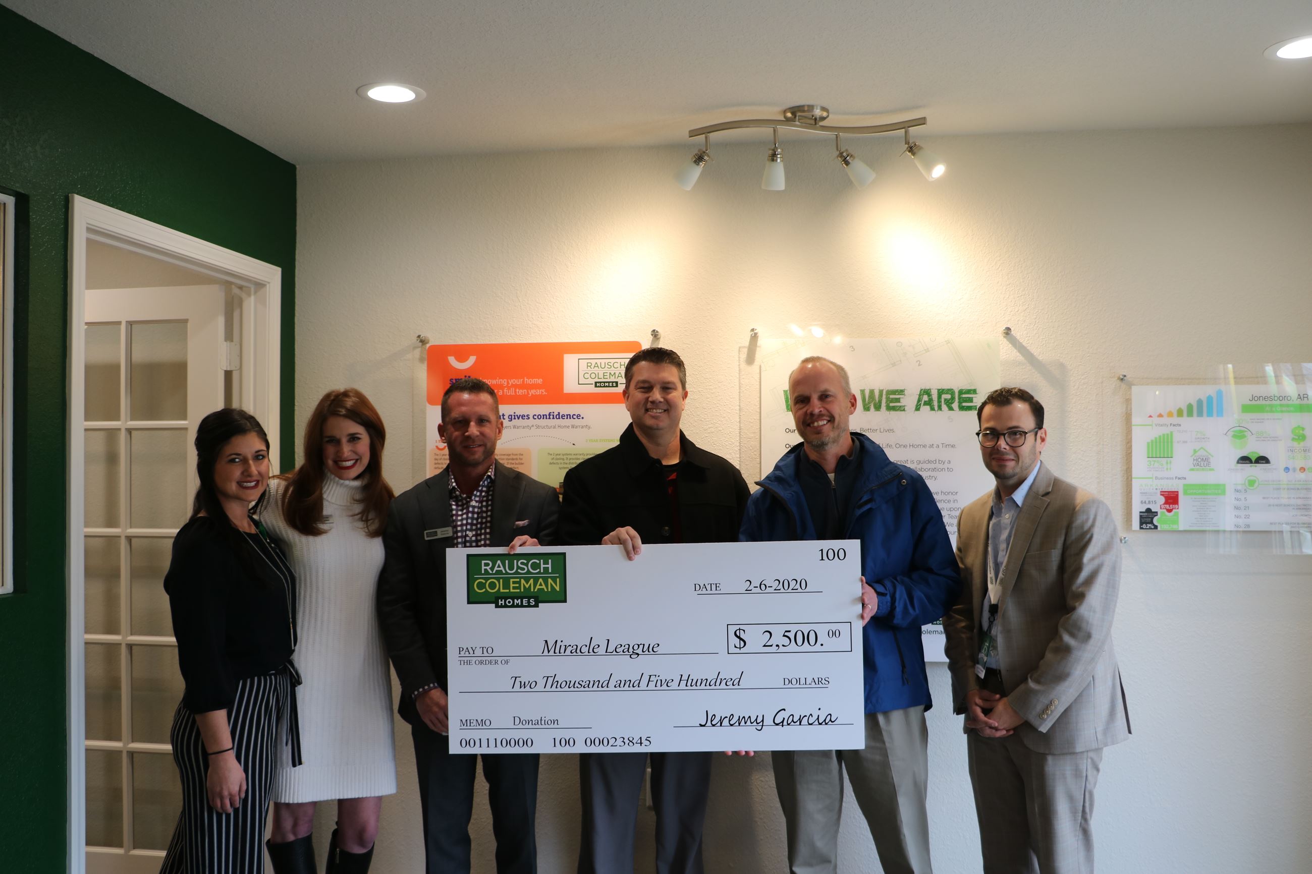 People stand holding large Rausch Coleman Homes check for $2,500 for Miracle League