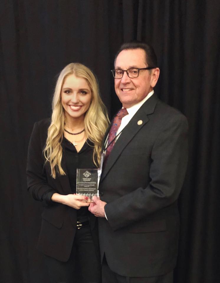 Executive Director Lindsey Wingo holds the award along with Mayor Harold Perrin