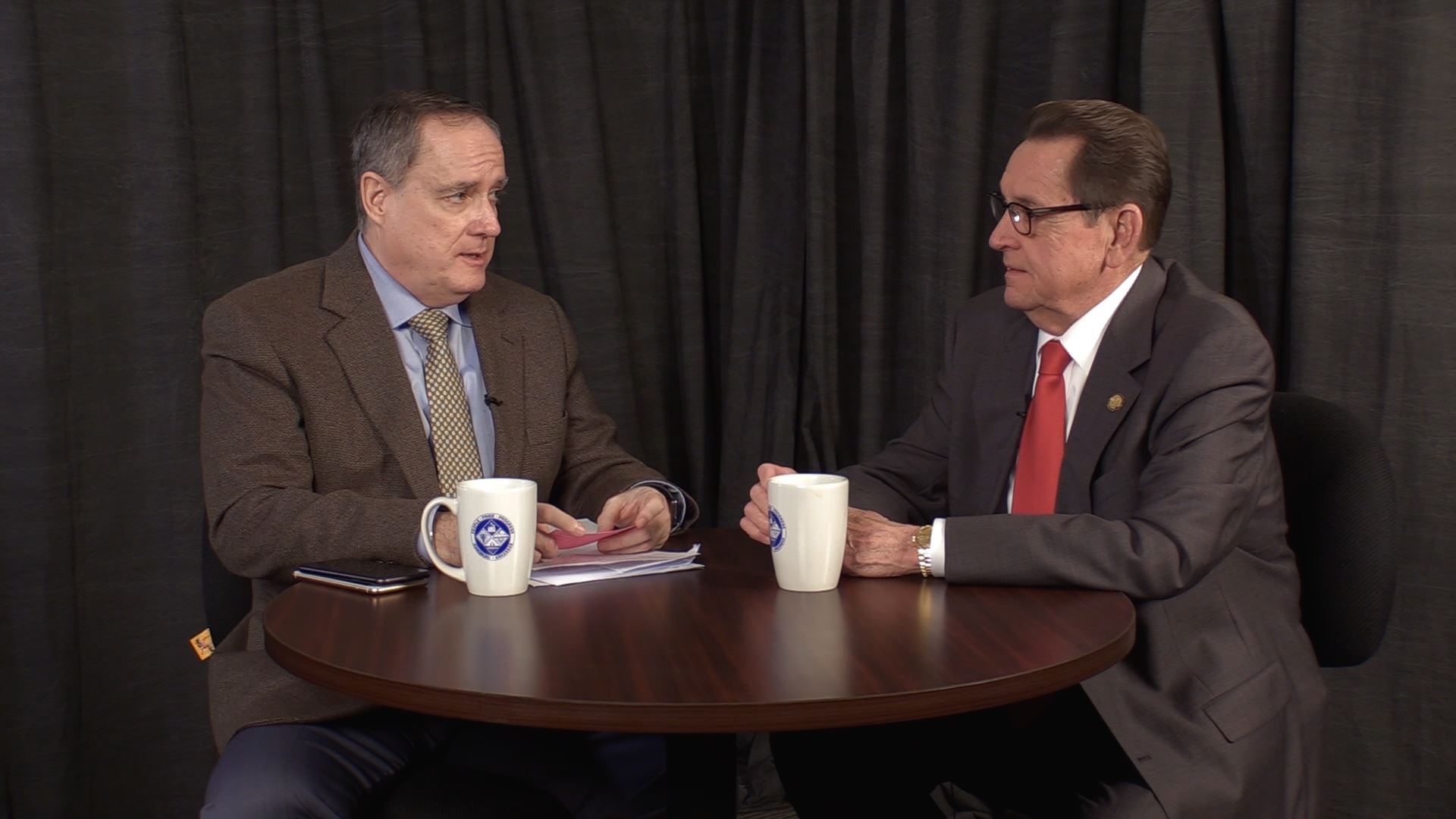 Host Bill Campbell interviewing Mayor Harold Perrin at a table on the show