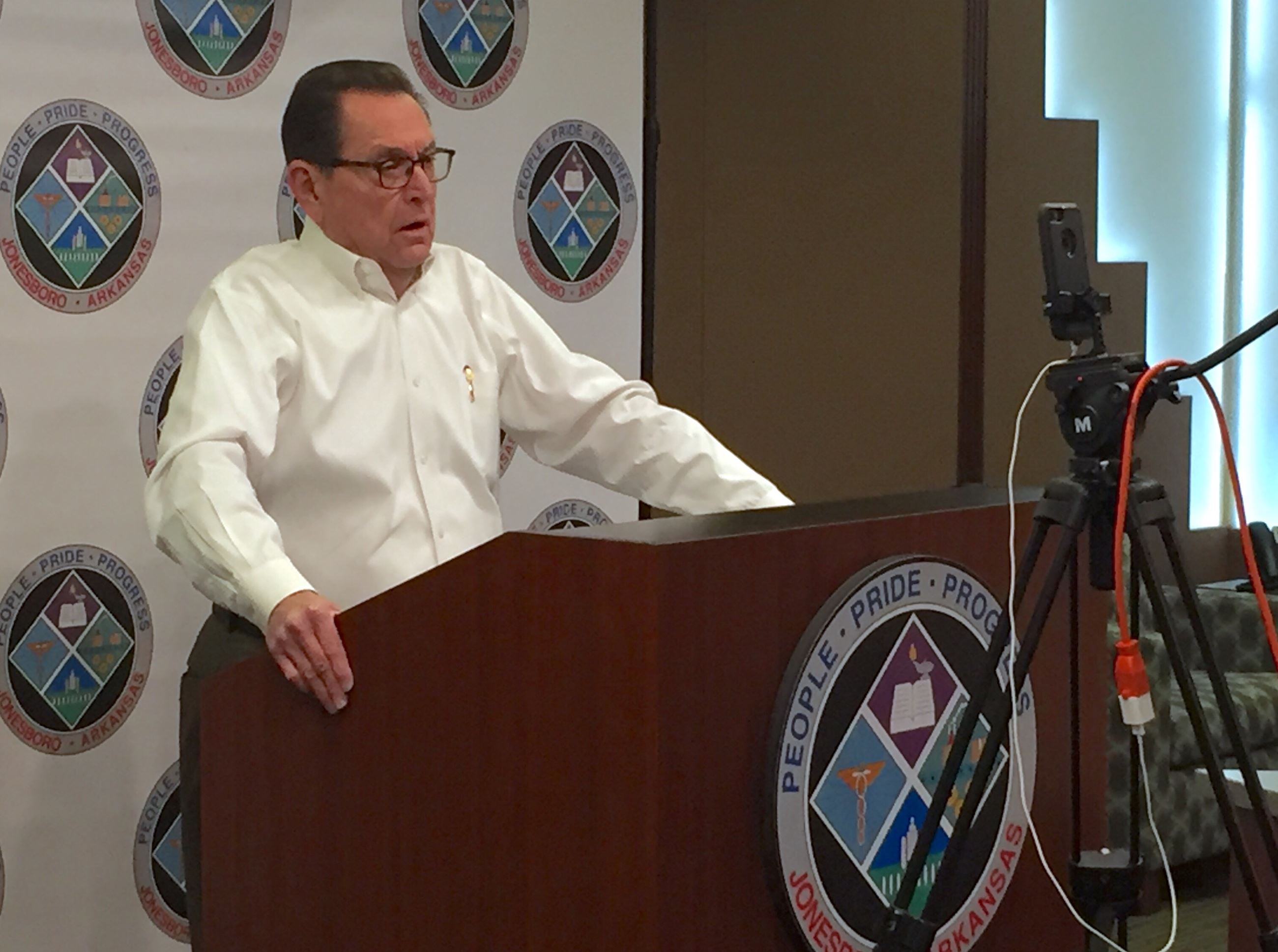 Mayor Perrin at a podium speaking to the the Kiwanis club online by video through a phone set up on 