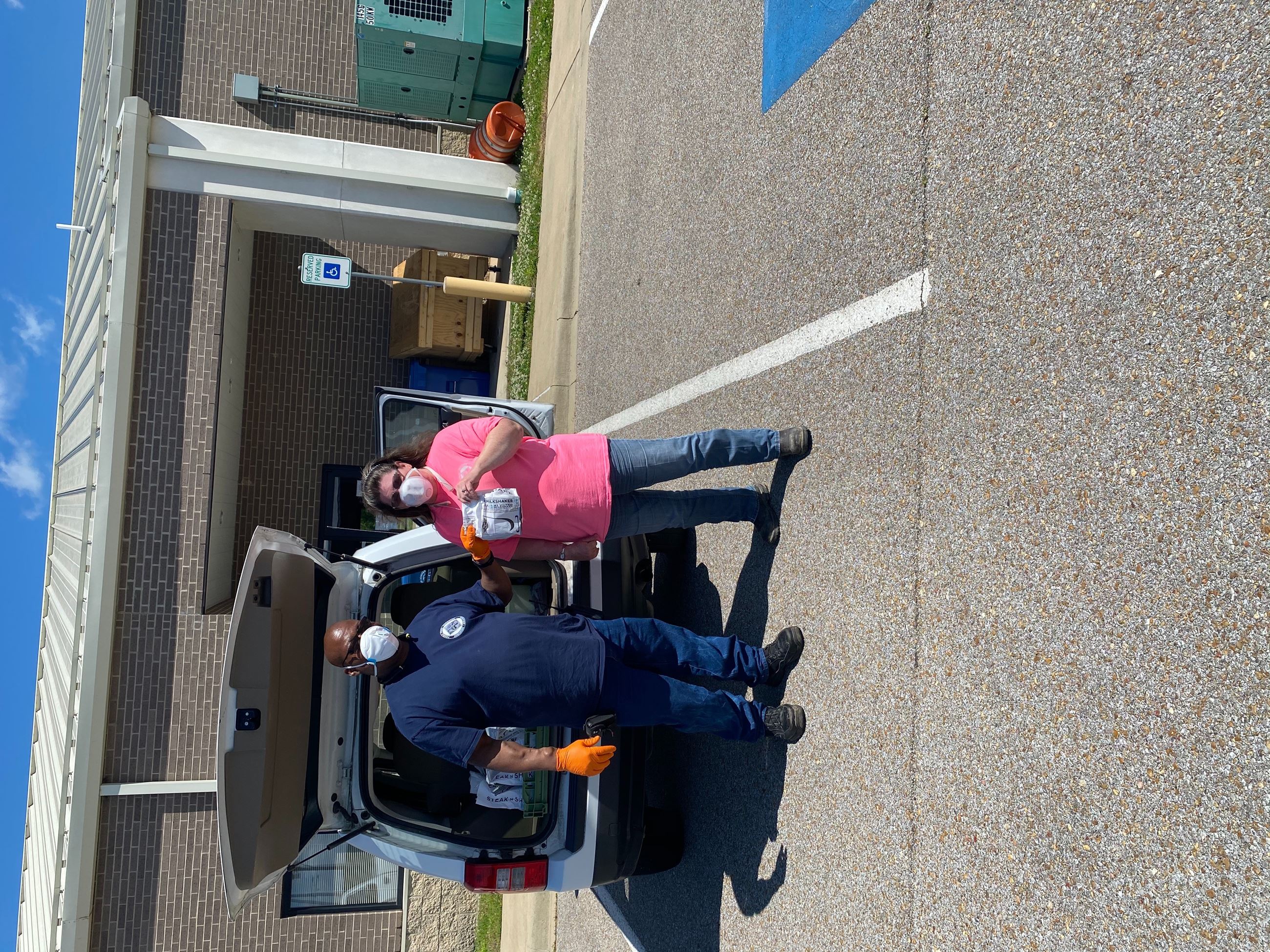 Steak 'n Shake's Ronny Stanback handing food to Sanitation employee Judy Fletcher, both with m