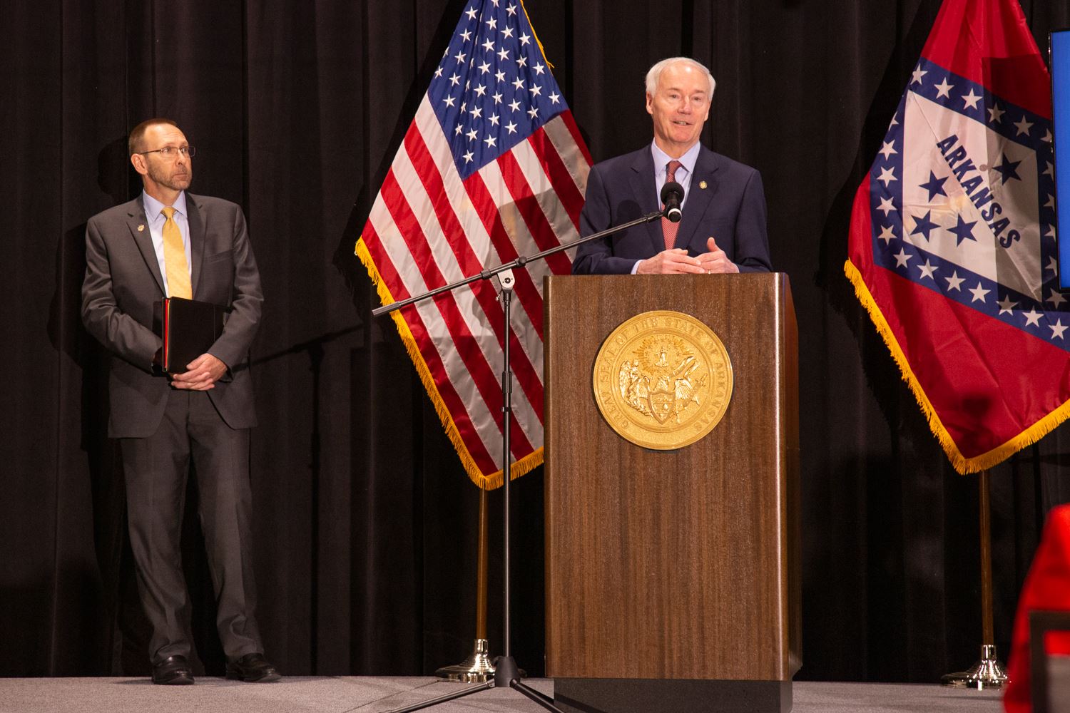 Governor Hutchinson speaking on stage and on television 