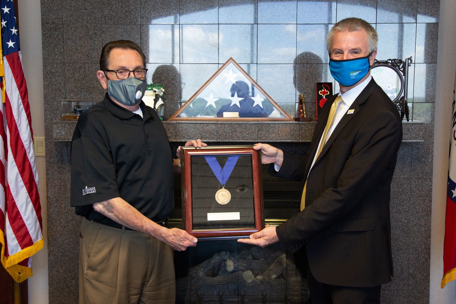 Mayor Harold Perrin and Dr. Shane Speights holding the Riland Medal in a frame