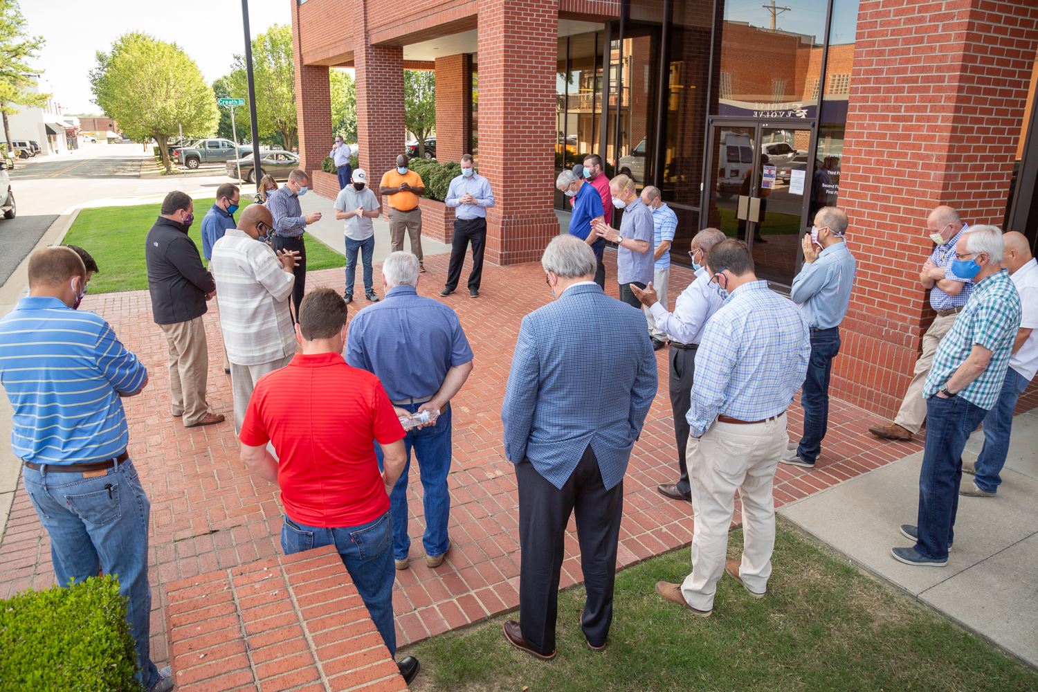 Pastors, Mayor Perrin and other officials standing in circle praying together