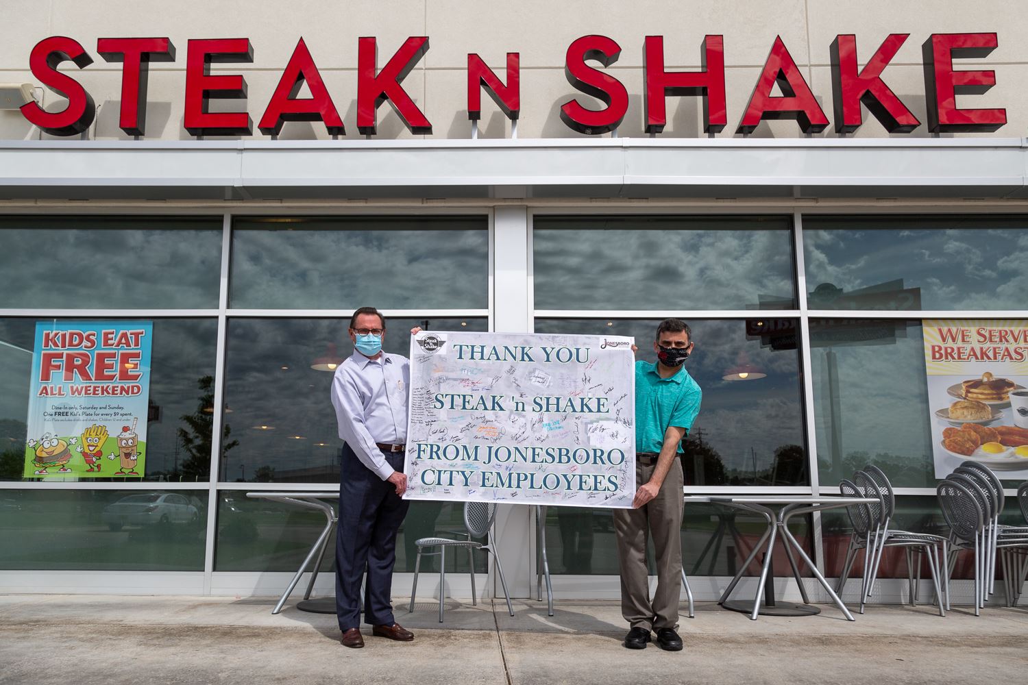 Mayor Perrin and General Manager hold the thank you poster in front of Steak 'n Shake