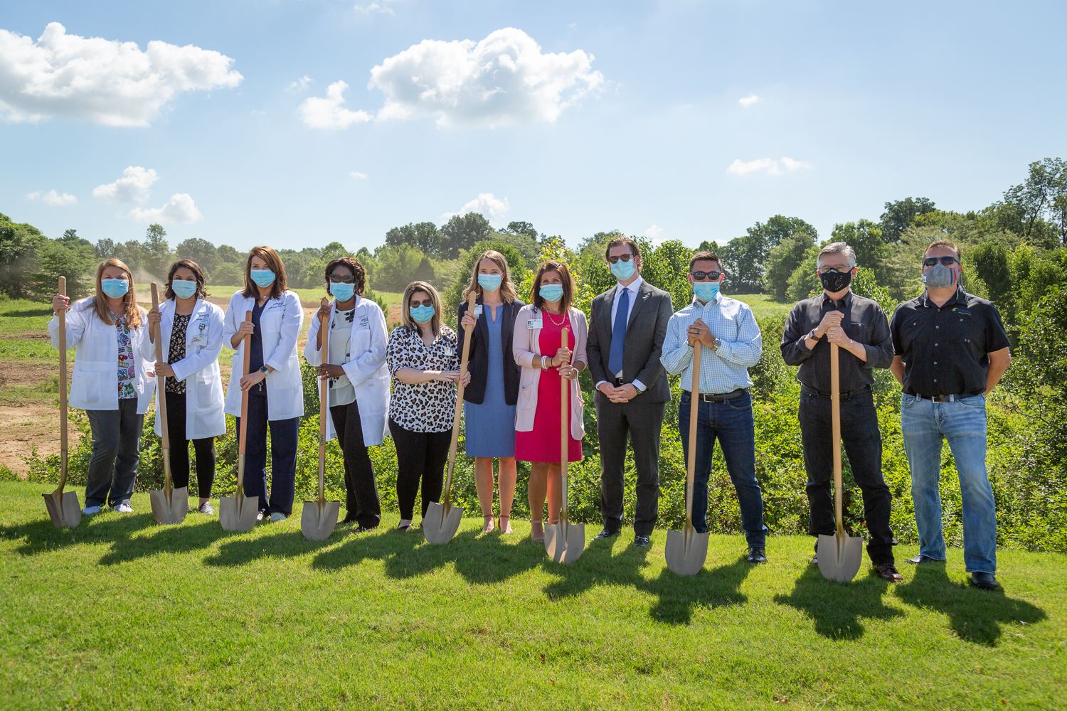NEA Baptist and Haag Brown officials standing in a line with shovels ready to break ground