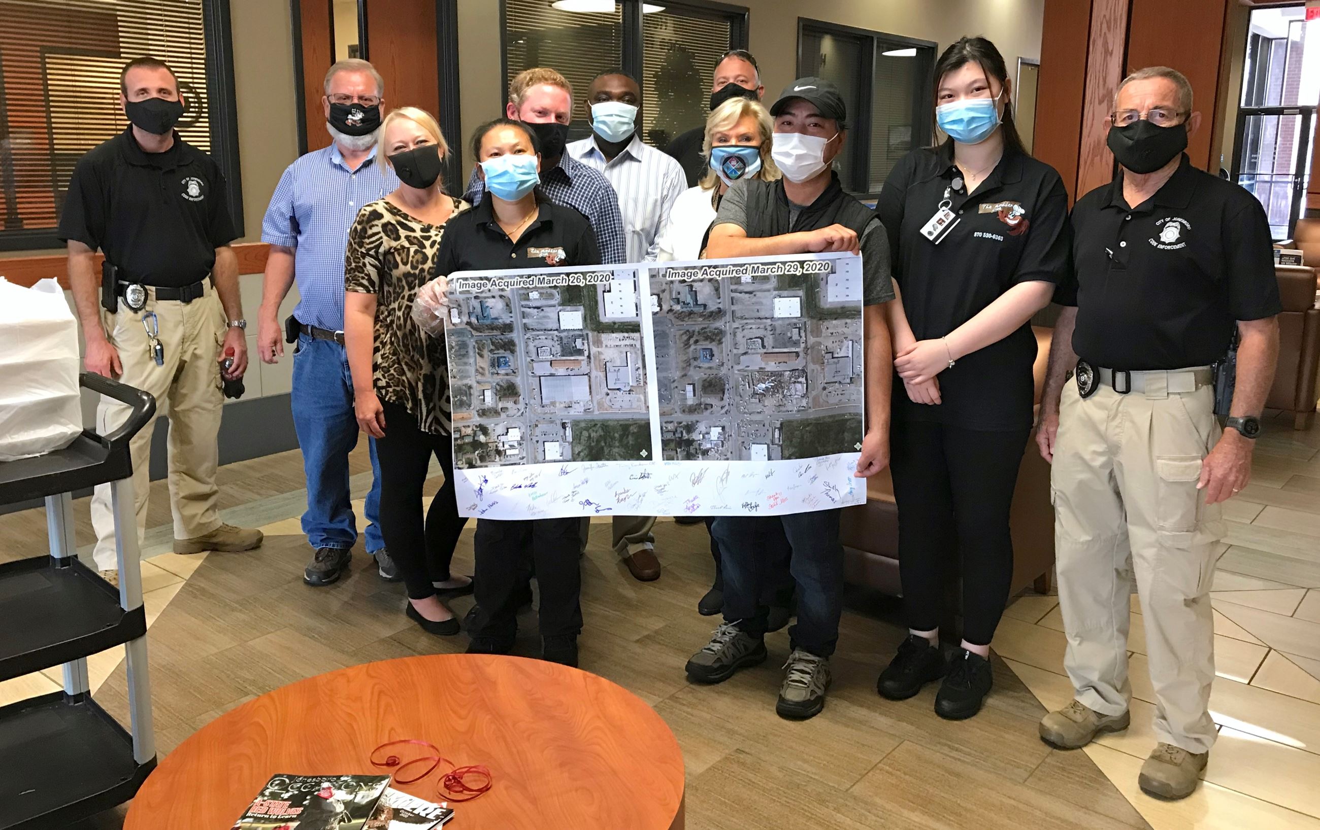 City of Jonesboro and The Madden Crab employees holding a banner with signatures and aerial photos
