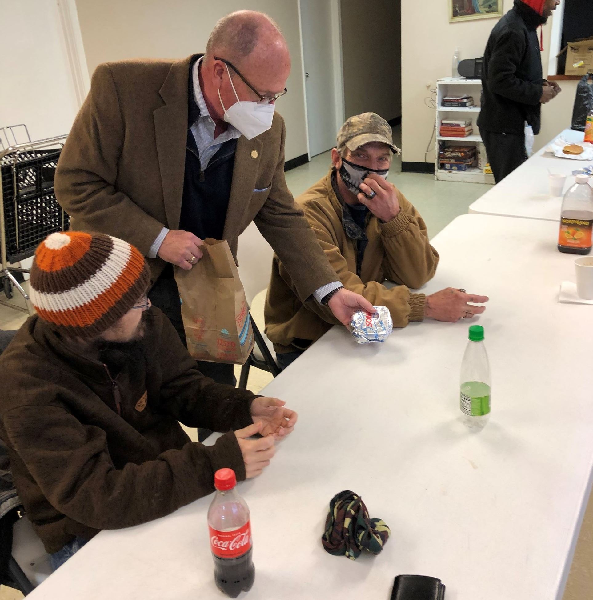 Mayor Copehaver gives a burger to people at the Salvation Army