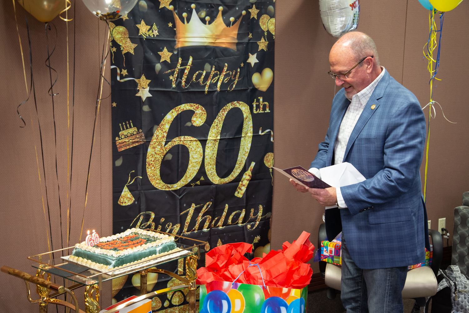 Mayor Copenhaver reading a birthday card with decorations and cake next to him