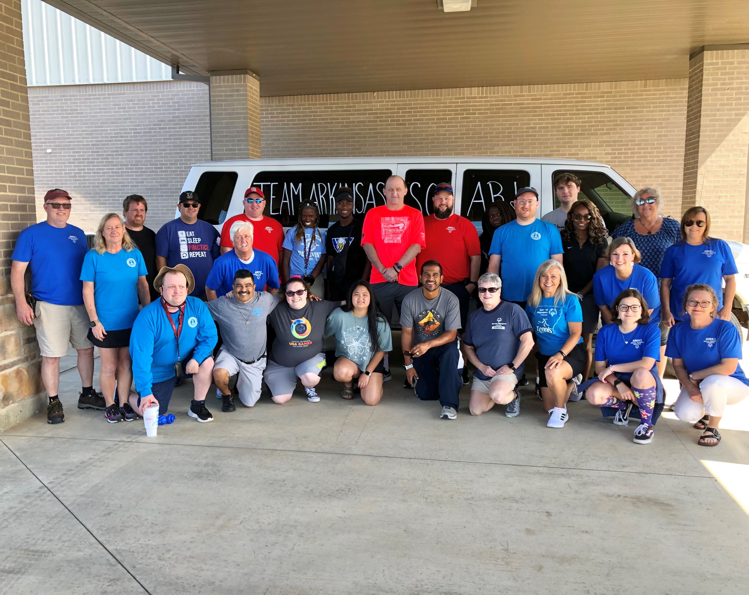 Team members posing in front of van for group photo