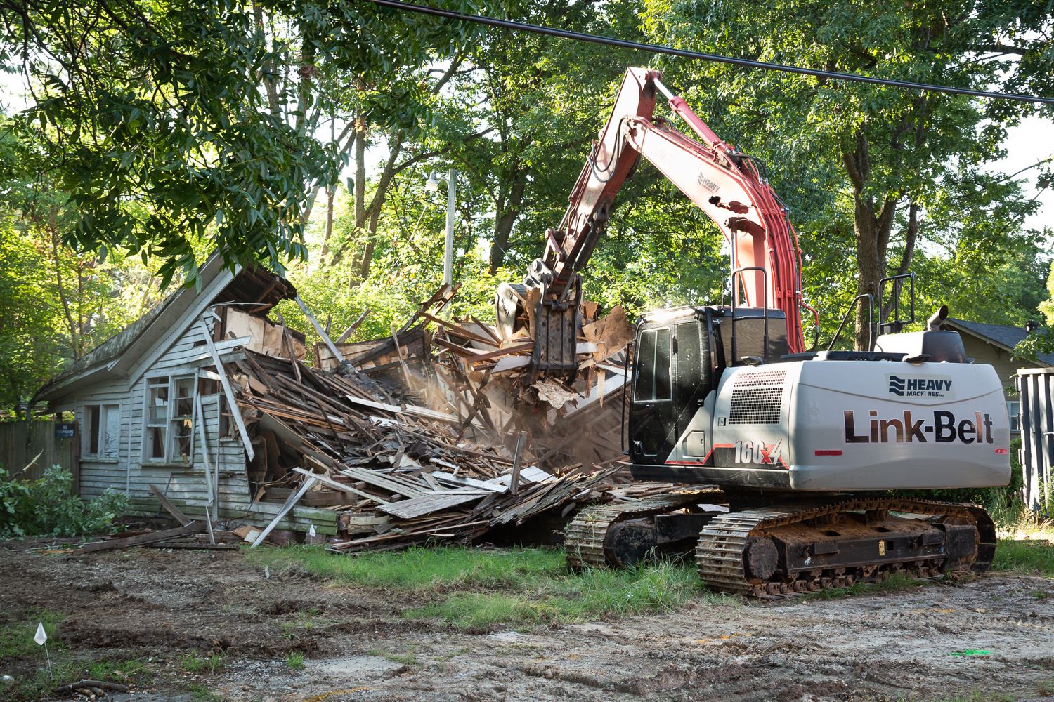 Track hoe demolishing old condemned house