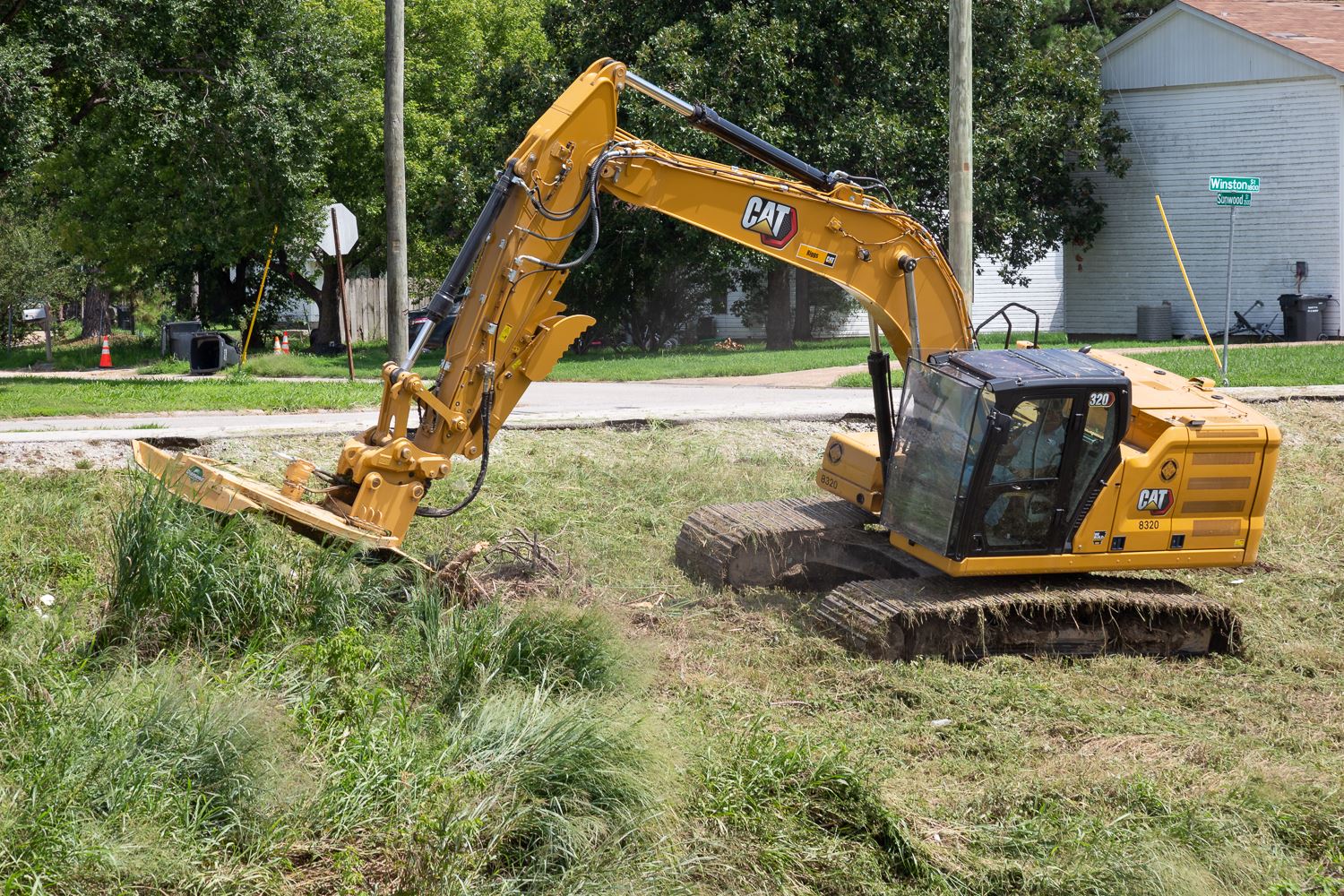 Excavator with mower mowing tall grass