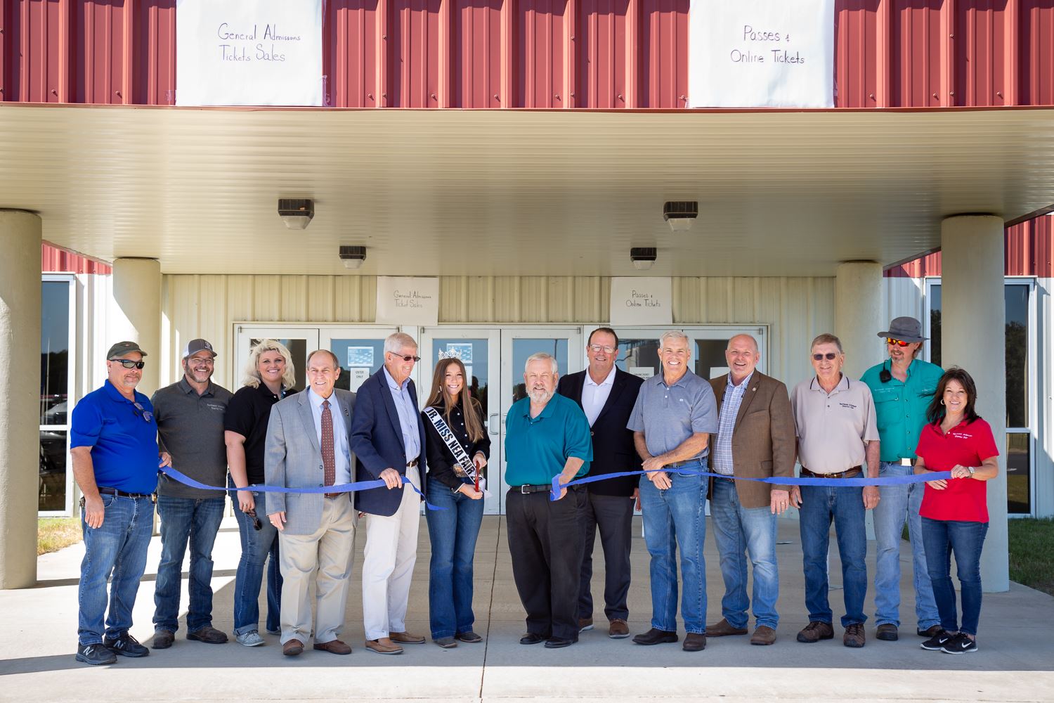 Notable people stand with ribbon as girl cuts it with giant scissors