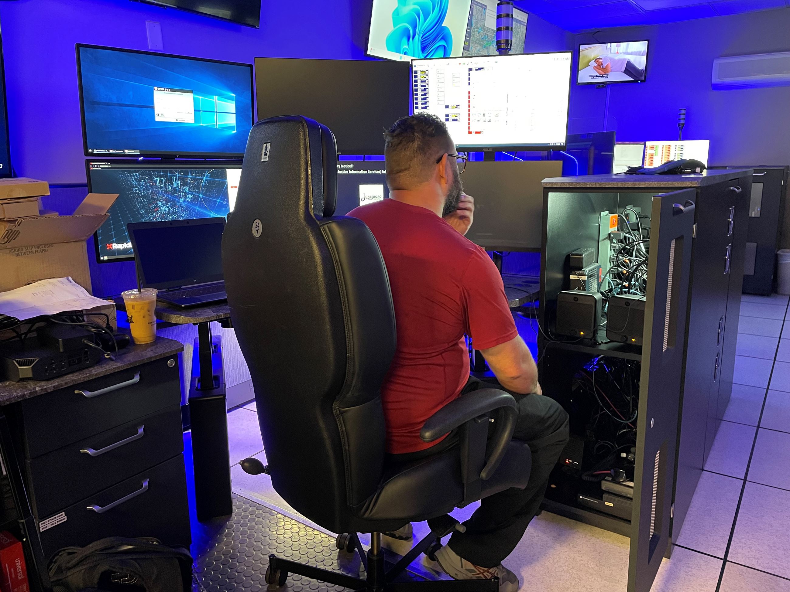 A technician looks at an opened cabinet full of wires and parts at a new computer console desk 