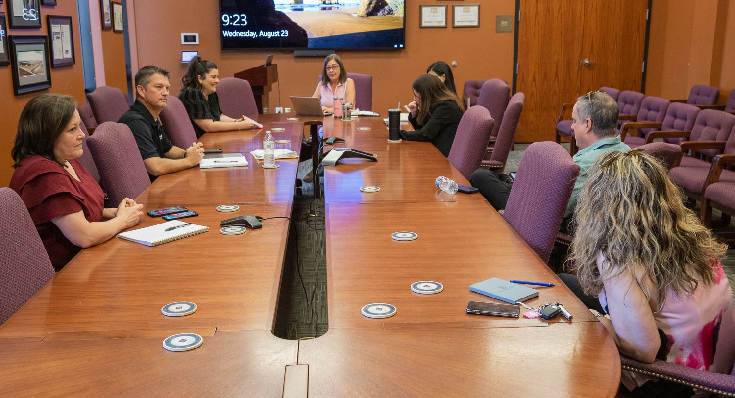 Members of Eclipse Committee meeting sit around board room table discussing things