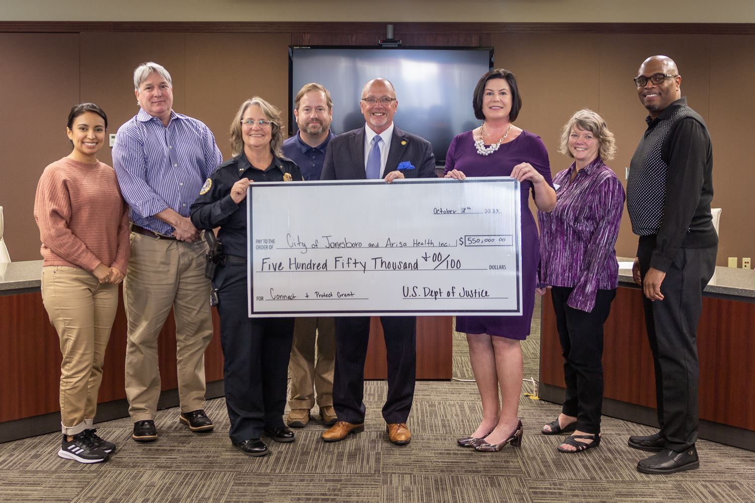 Arisa Health and city employees standing together with large check