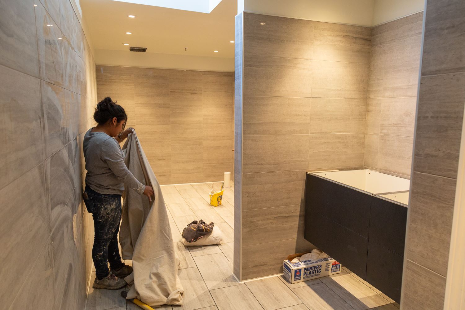 Worker with drop cloth working on renovating restroom